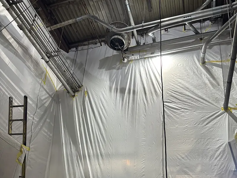 Large warehouse ceiling with asbestos containment sheeting all the way up the walls